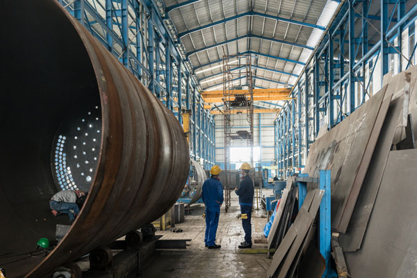 workers in manufacturing plant with large metal cylanders