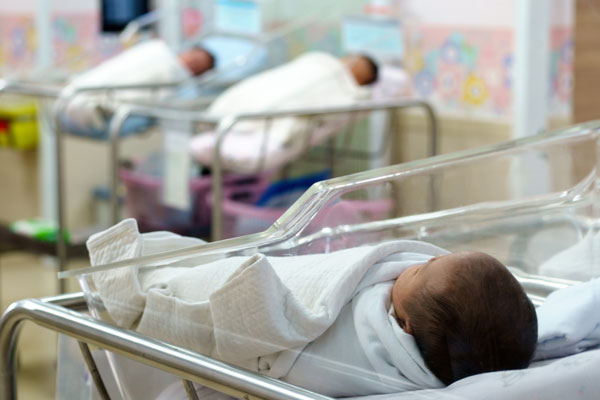 Image of a newborn baby swaddled in a hospital delivery room.